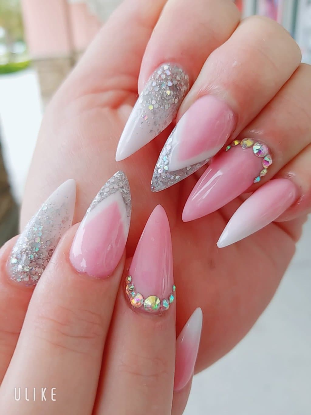Pointed nails with silver glitter, white tips and arcs of crystals on pink